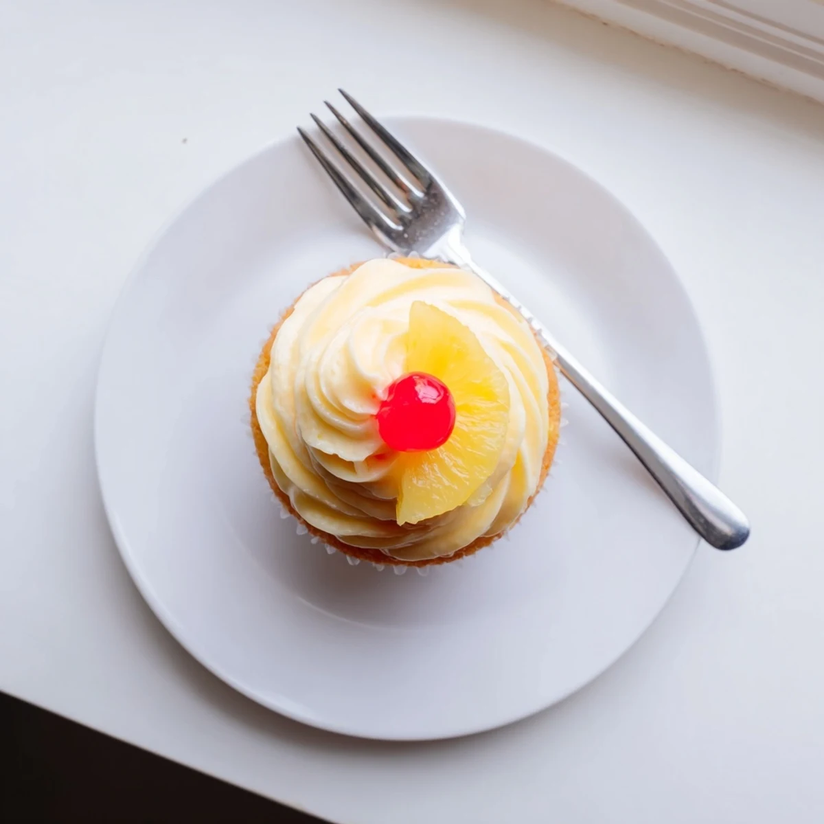 Golden Dole Whip Cupcakes topped with fluffy pineapple whipped frosting and a cherry garnish