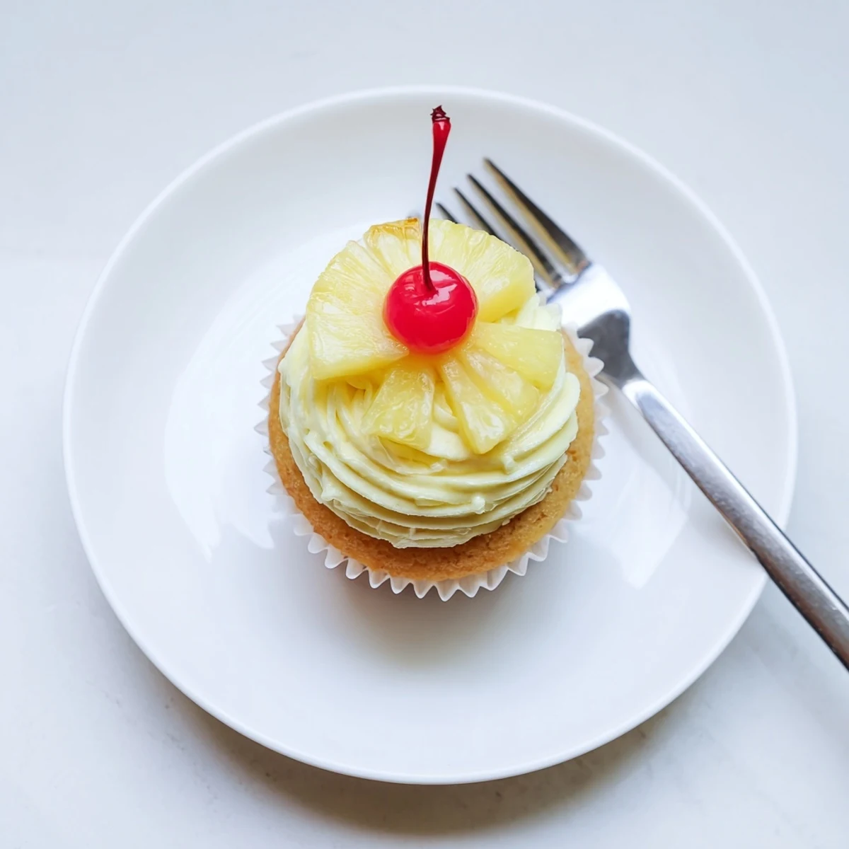 A batch of freshly baked Dole Whip Cupcakes with light whipped pineapple frosting and pineapple wedges