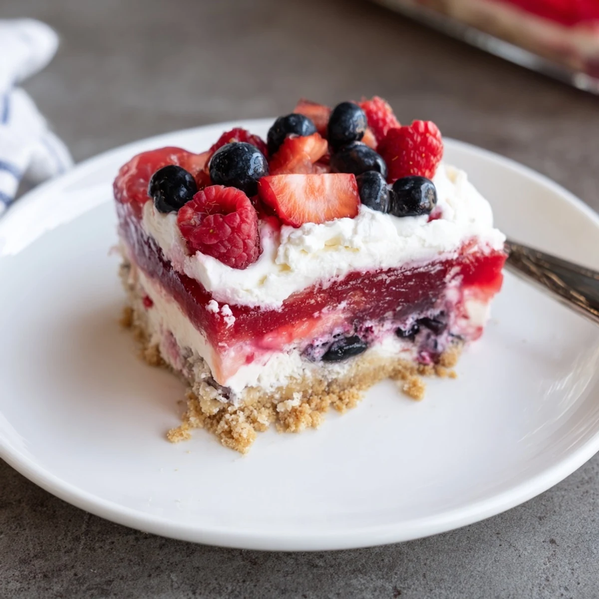 Summer Berry Jello Lasagna chilled in a glass dish, glossy berries and creamy layers