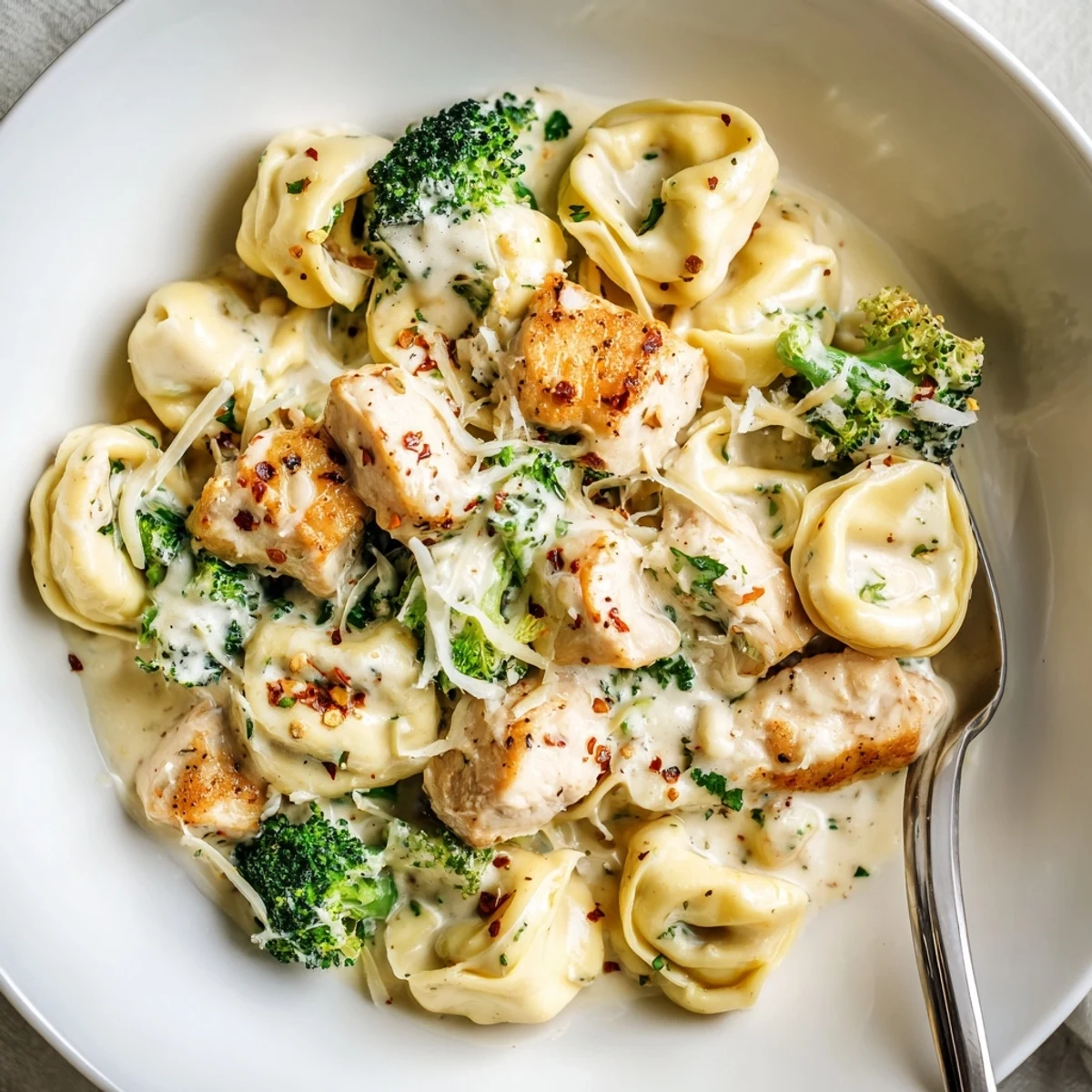Creamy Garlic Parmesan Tortellini Chicken Broccoli Recipe steaming, saucy pasta with golden chicken