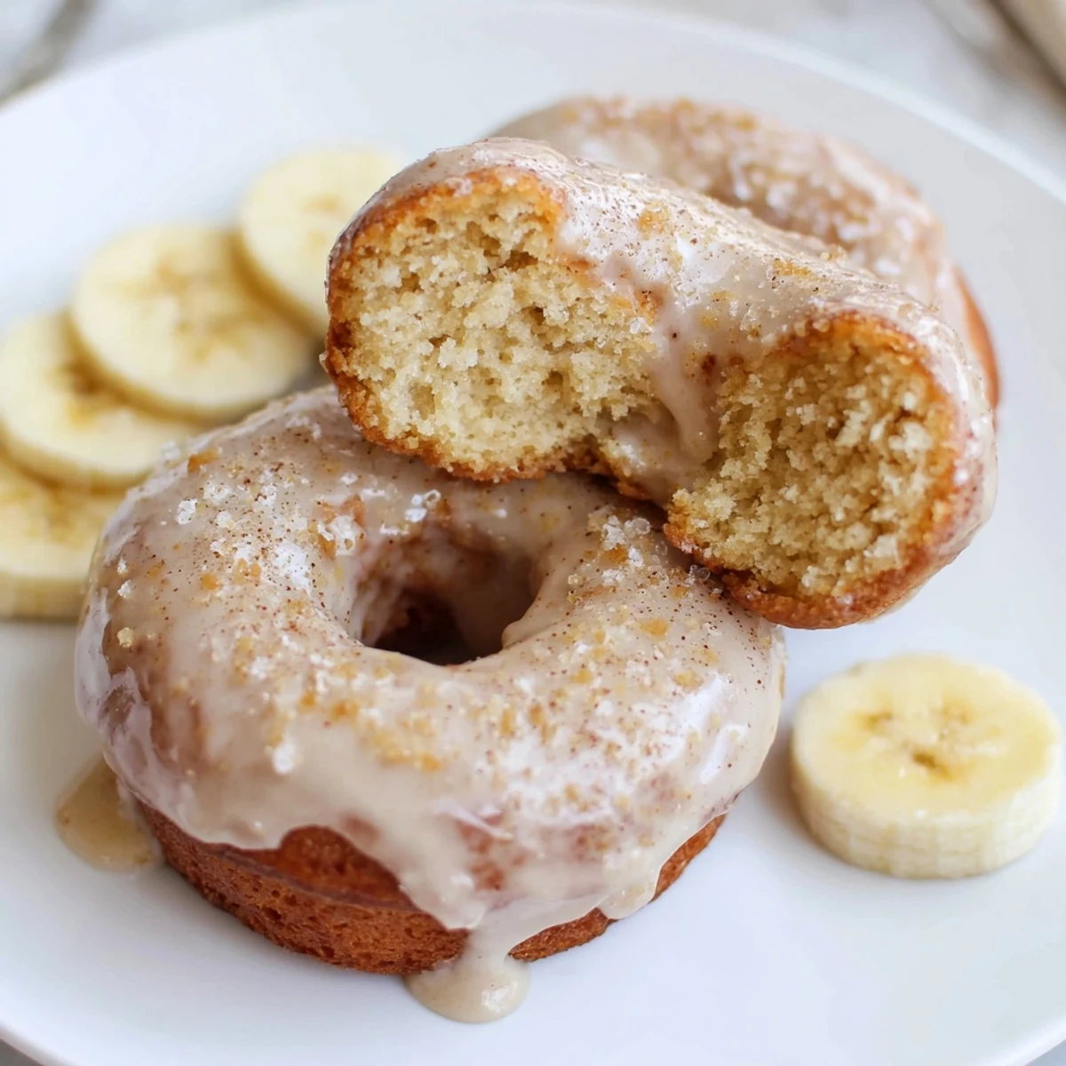 Fresh-baked Banana Donuts with golden tops, soft crumb and vanilla glaze.
