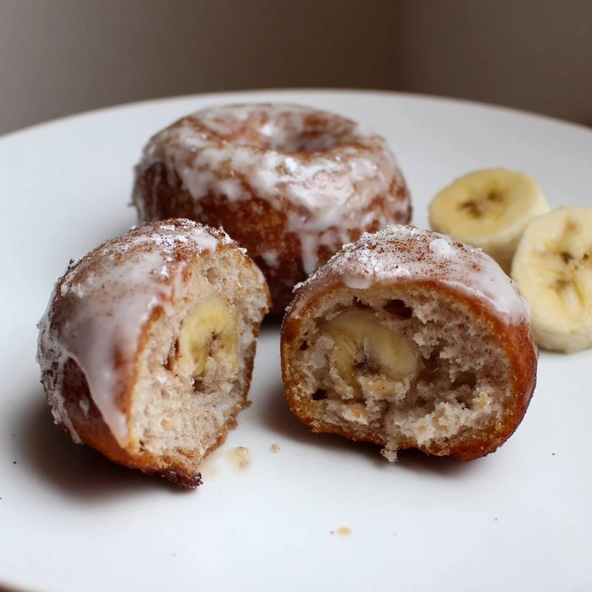 Plate of glazed Banana Donuts beside coffee, fluffy, banana aroma rising.