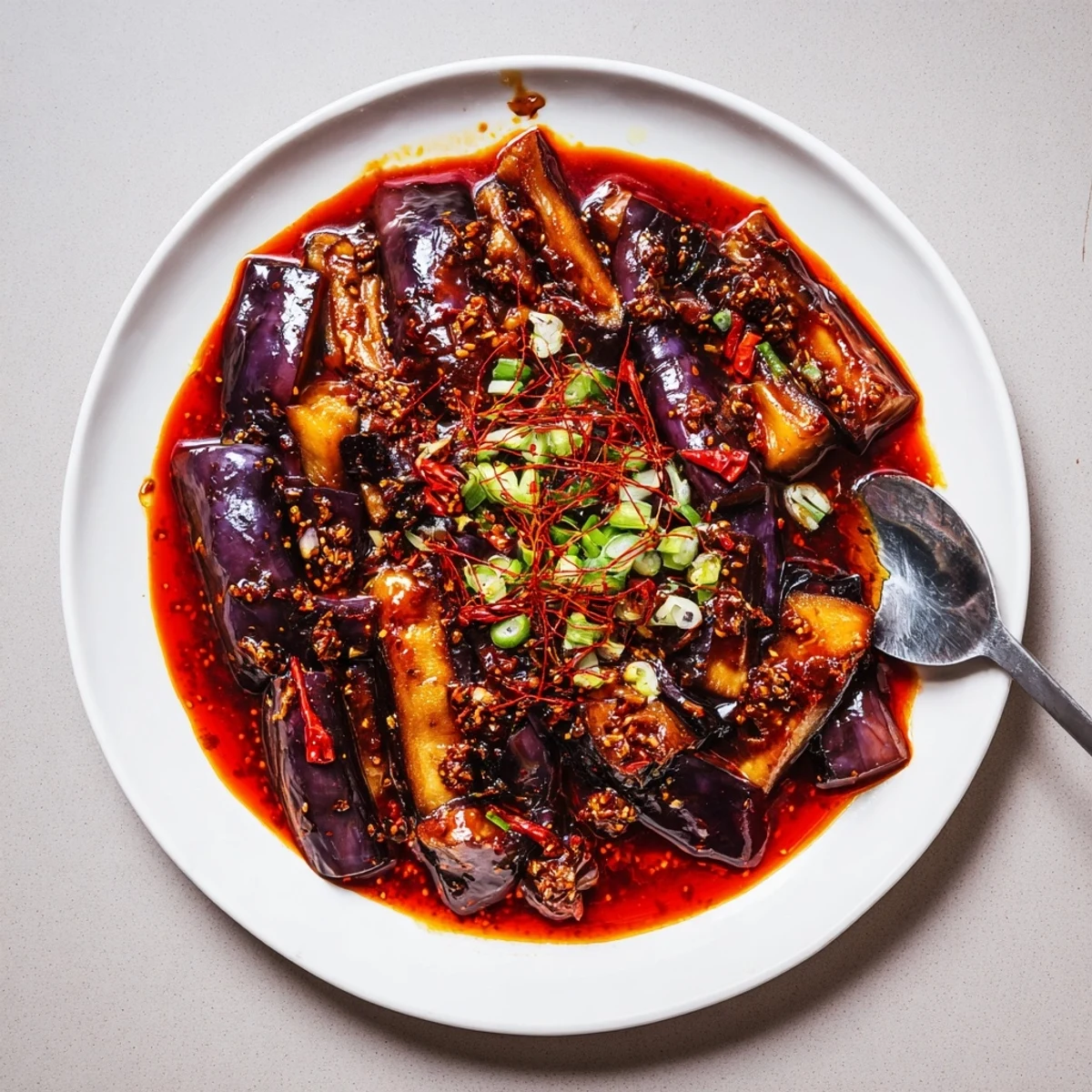 Sichuan Style Braised Aubergines glistening in spicy red sauce over rice