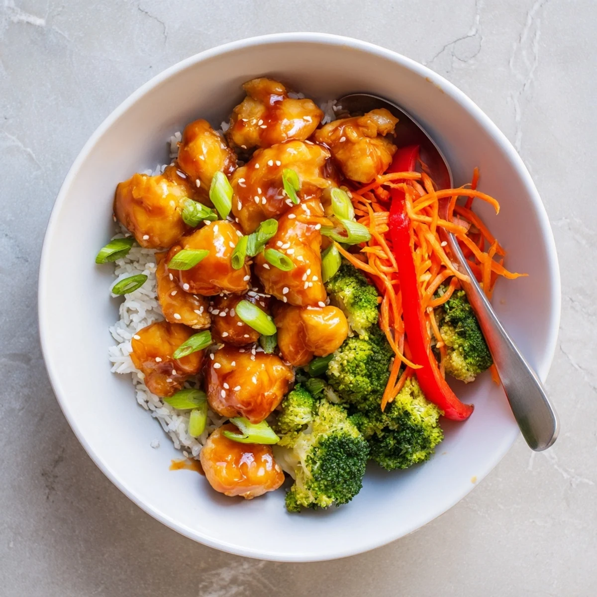 Vibrant rice bowl with sweet orange glazed chicken and colorful fresh vegetables