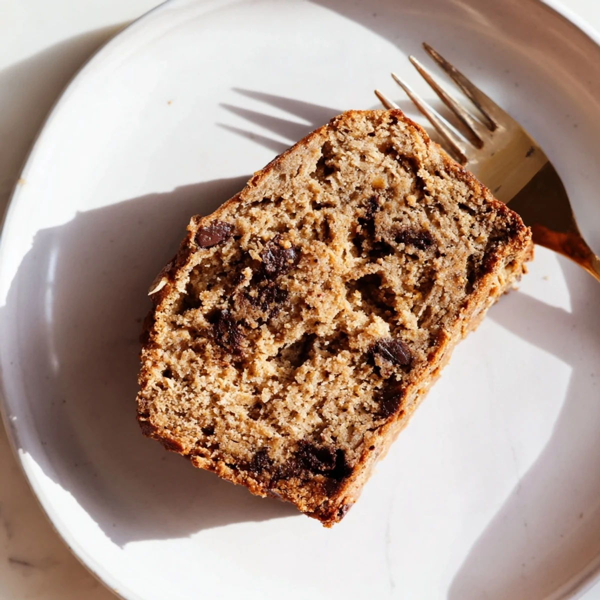 Wholesome protein banana bread muffins topped with dark chocolate chips and banana slices