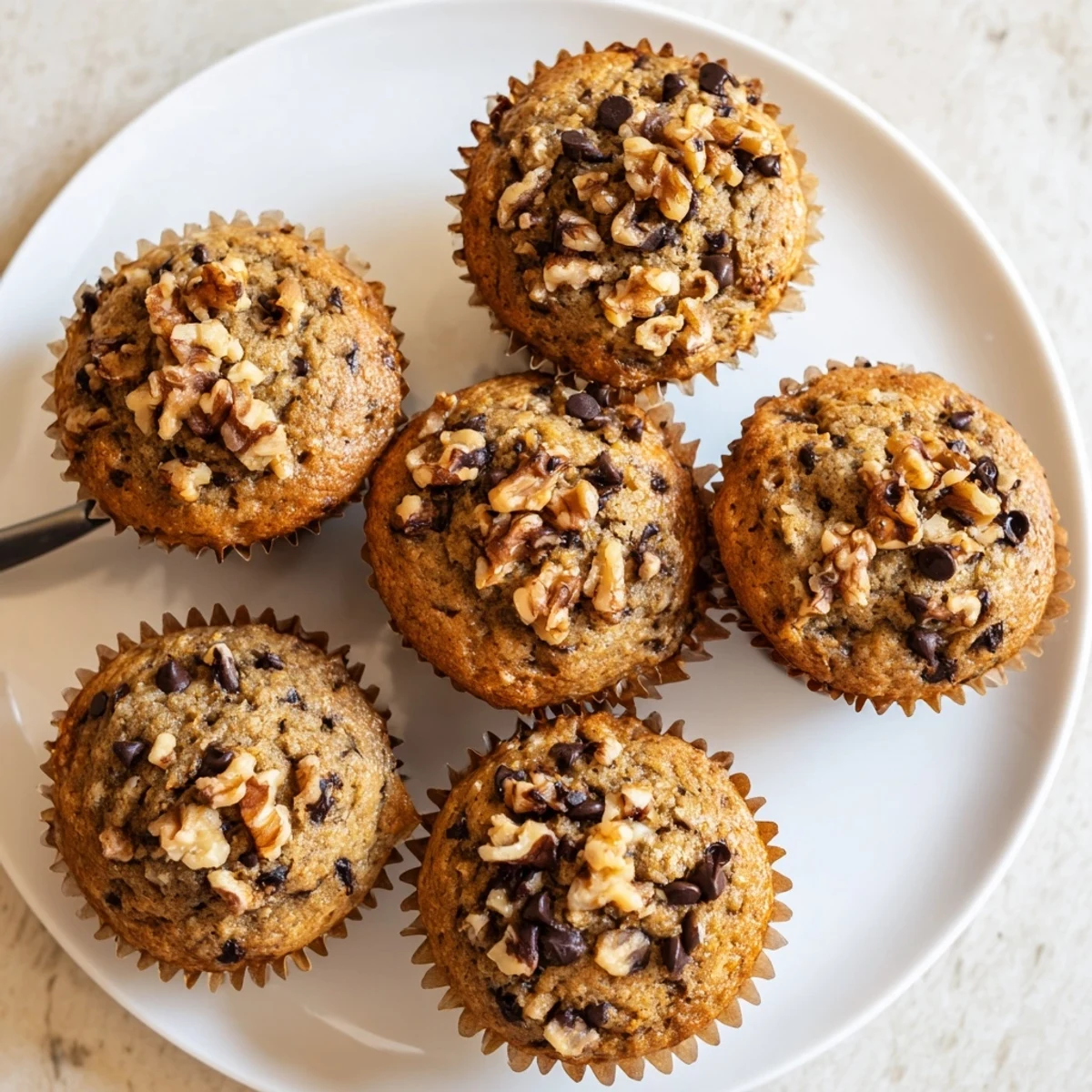Golden brown healthy banana nut muffins topped with chopped walnuts on a wire cooling rack