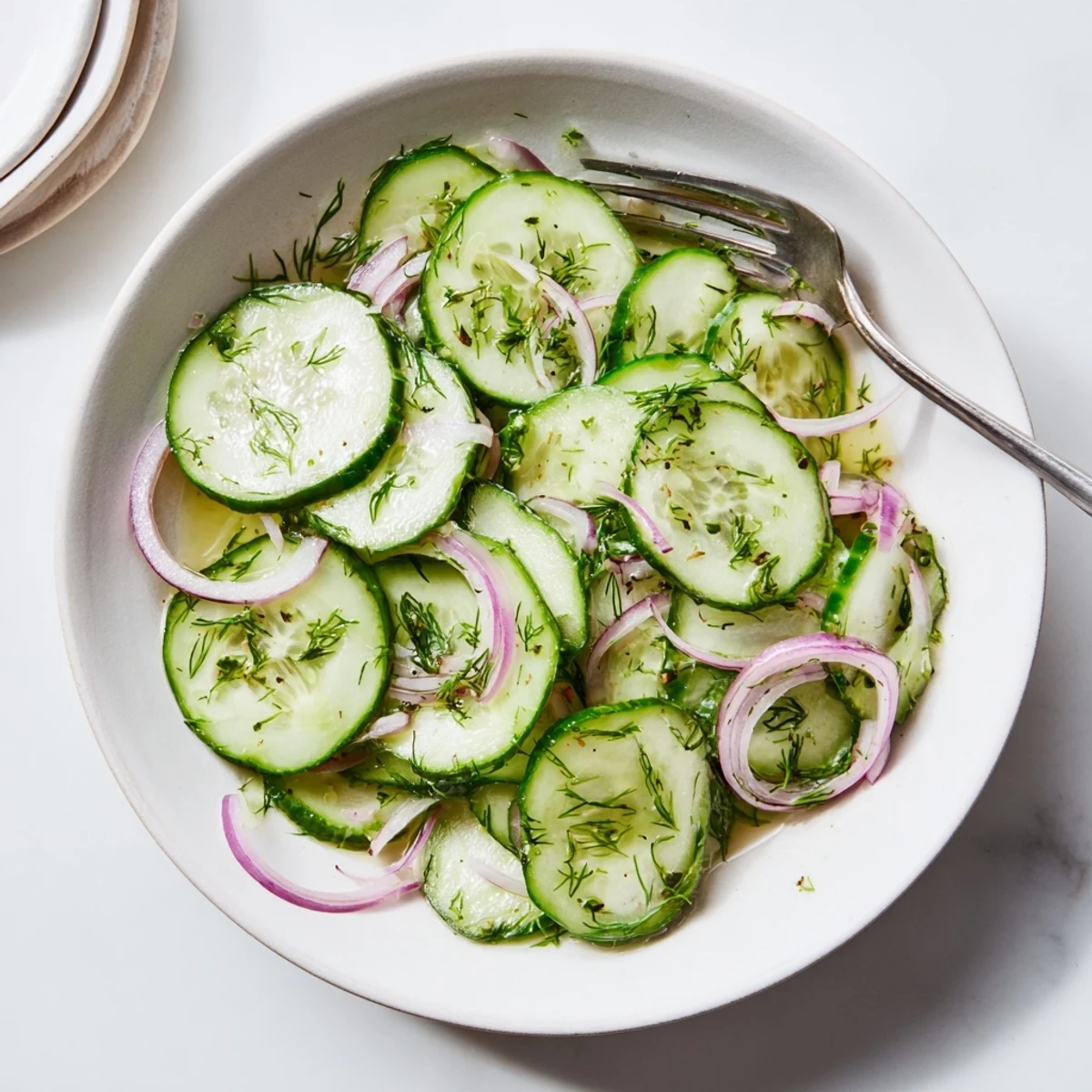 Refreshing cucumber salad bowl with crisp sliced cucumbers, red onions, and fresh dill in tangy vinaigrette