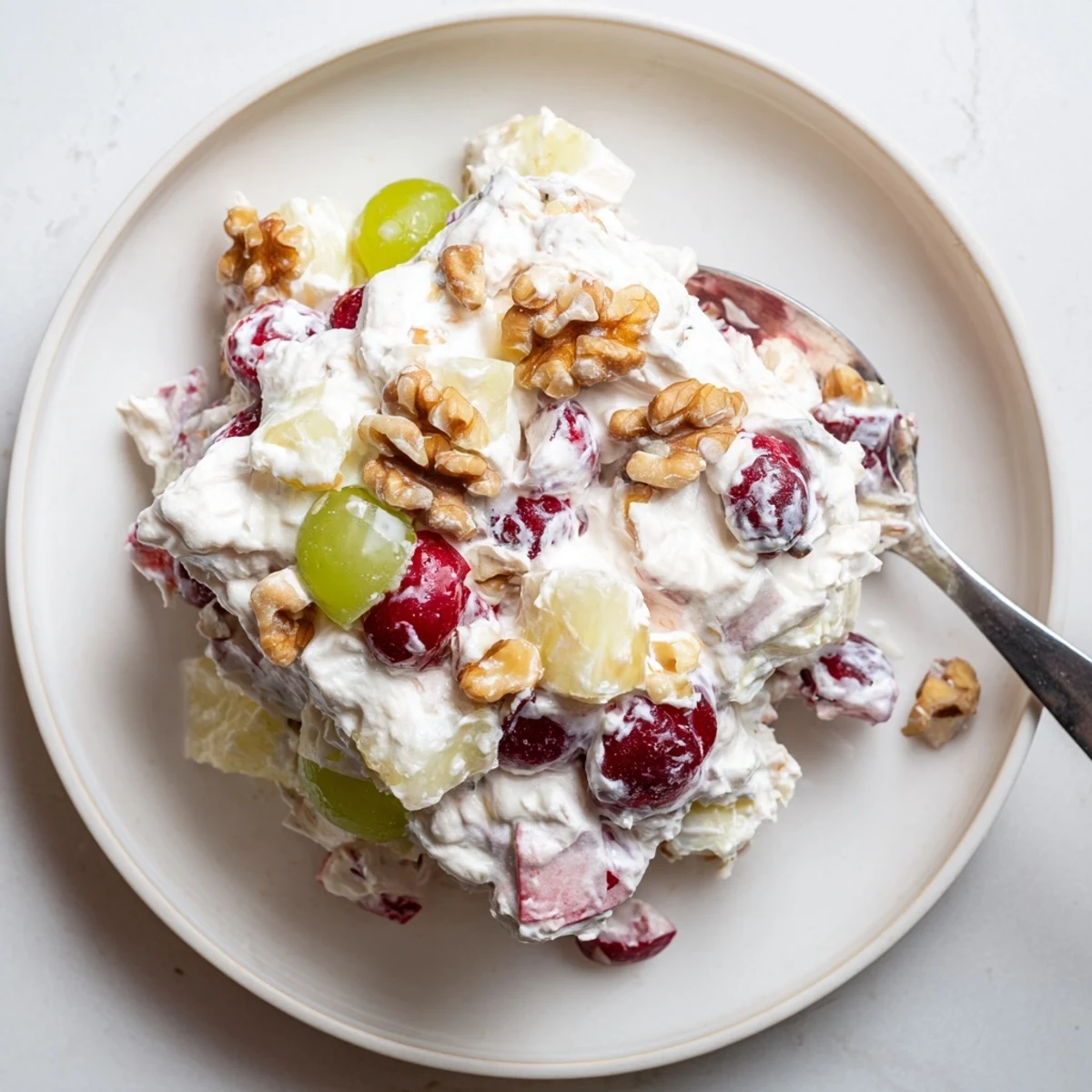 Scoop of frozen cranberry salad with red berries and creamy white swirls in glass bowl