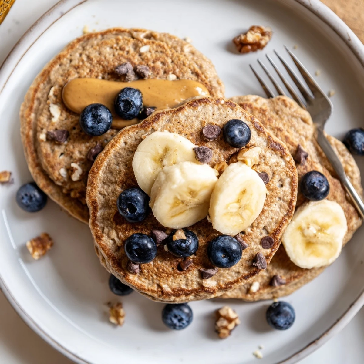 Two Protein Banana Pancakes on plate, sliced bananas and berry garnish