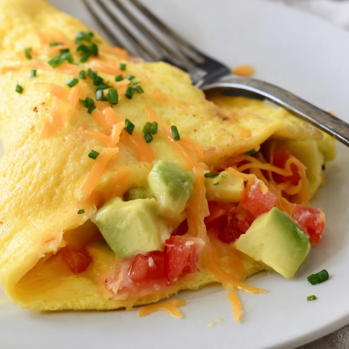 Creamy avocado cheesy tomato omelette served hot with gooey cheese and fresh diced tomatoes