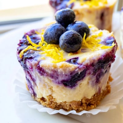 Creamy mini lemon blueberry cheesecakes swirling with tangy citrus and bursting ripe berries